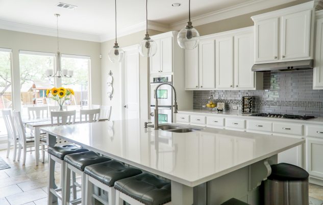 Spacious modern kitchen with white cabinets and island in natural light.