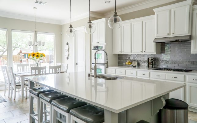 Spacious modern kitchen with white cabinets and island in natural light.