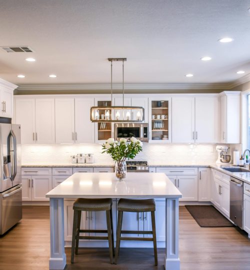 Spacious and elegant kitchen featuring white cabinetry, island, and stainless steel appliances.